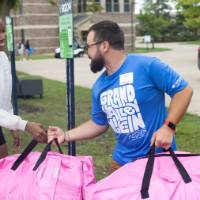 Volunteer carrying bright pink bag while shaking hands with new arrival